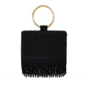 A black embroidered clutch with a golden handle and fringes, closed with a snap button.