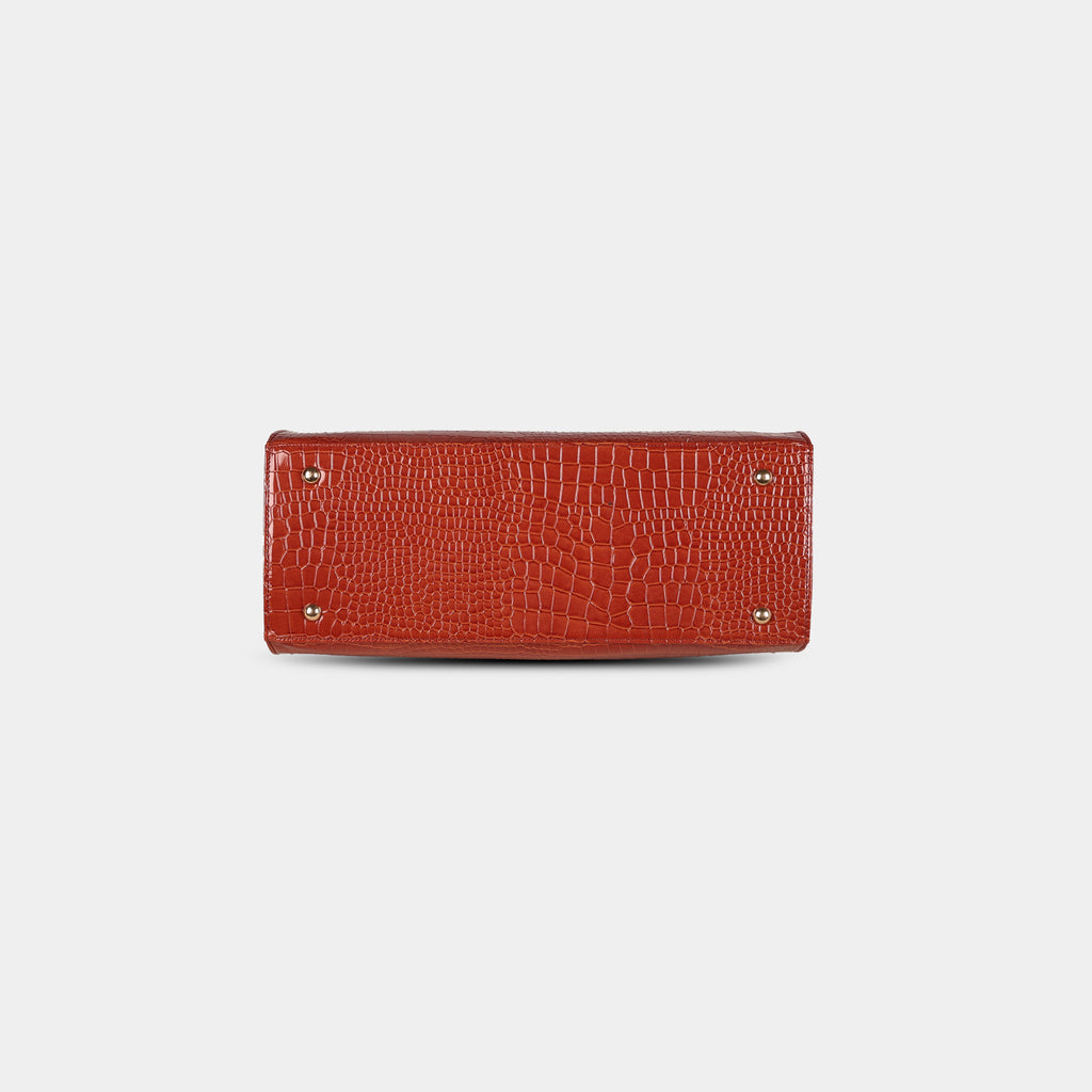 Bottom view of red snake-embossed handbag featuring four protective metal base studs