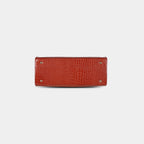 Bottom view of red snake-embossed handbag featuring four protective metal base studs