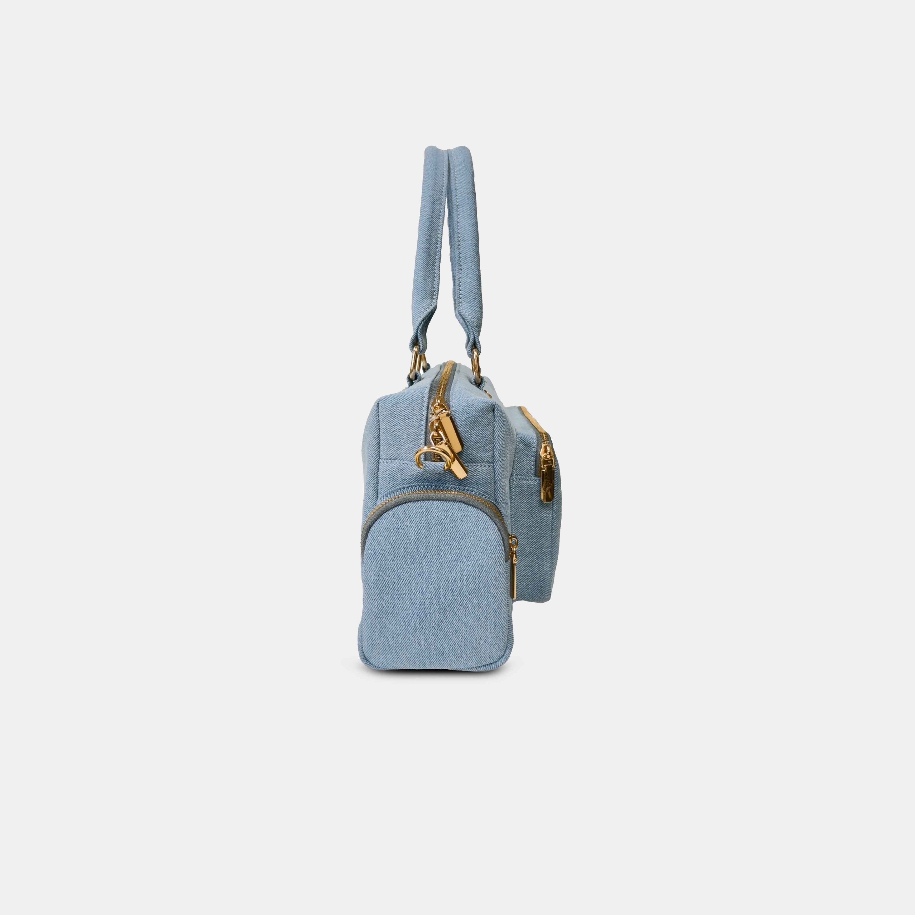 Side profile of light blue Frida denim sling bag highlighting side zipper pocket