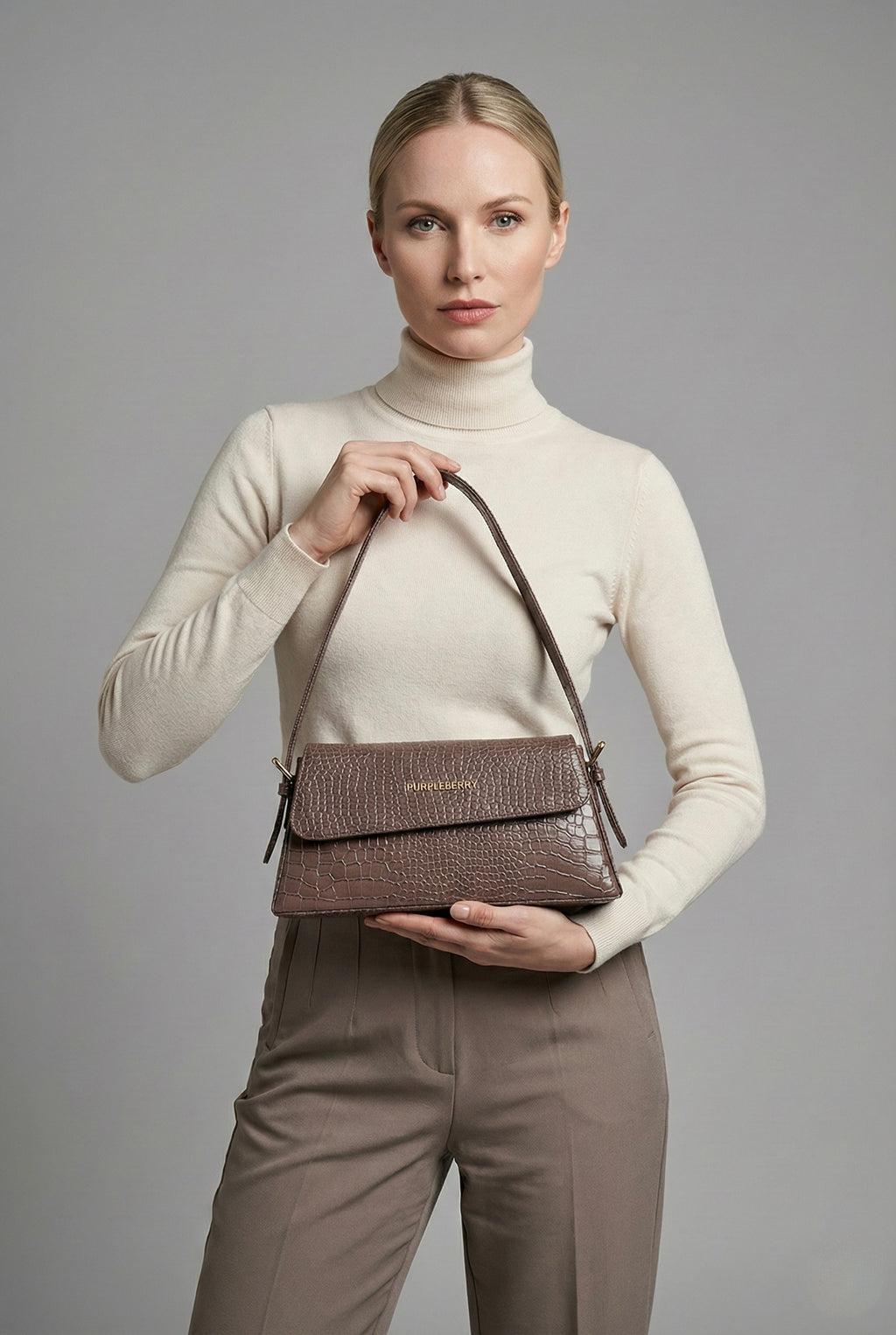 Model holding taupe Halo structured baguette shoulder bag at her stomach level 