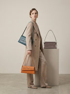 Model carrying teal Halo snake-embossed shoulder bag