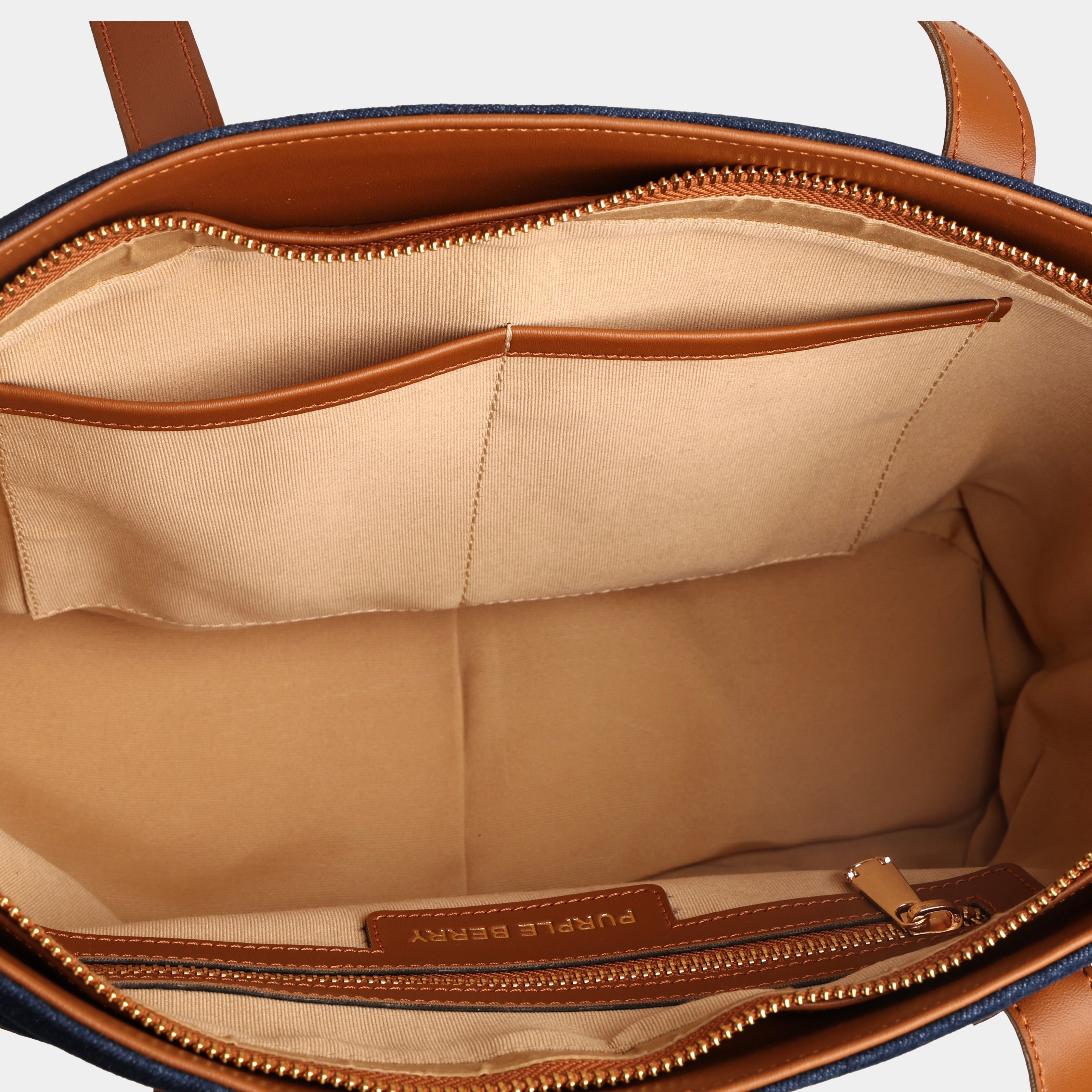 Interior of dark blue Harper denim handbag showing spacious main compartment with slip pockets and zipper pocket