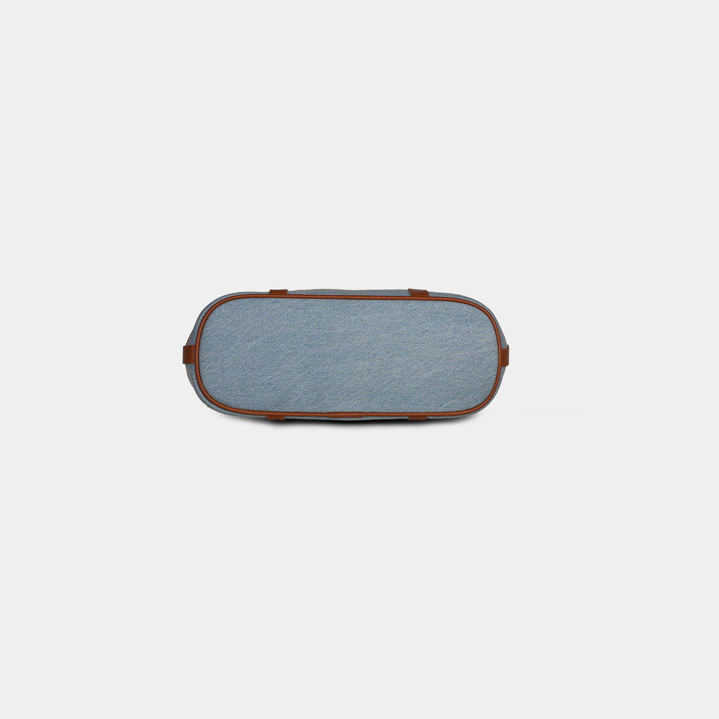 Bottom base of light blue Harper denim handbag with four protective metal studs