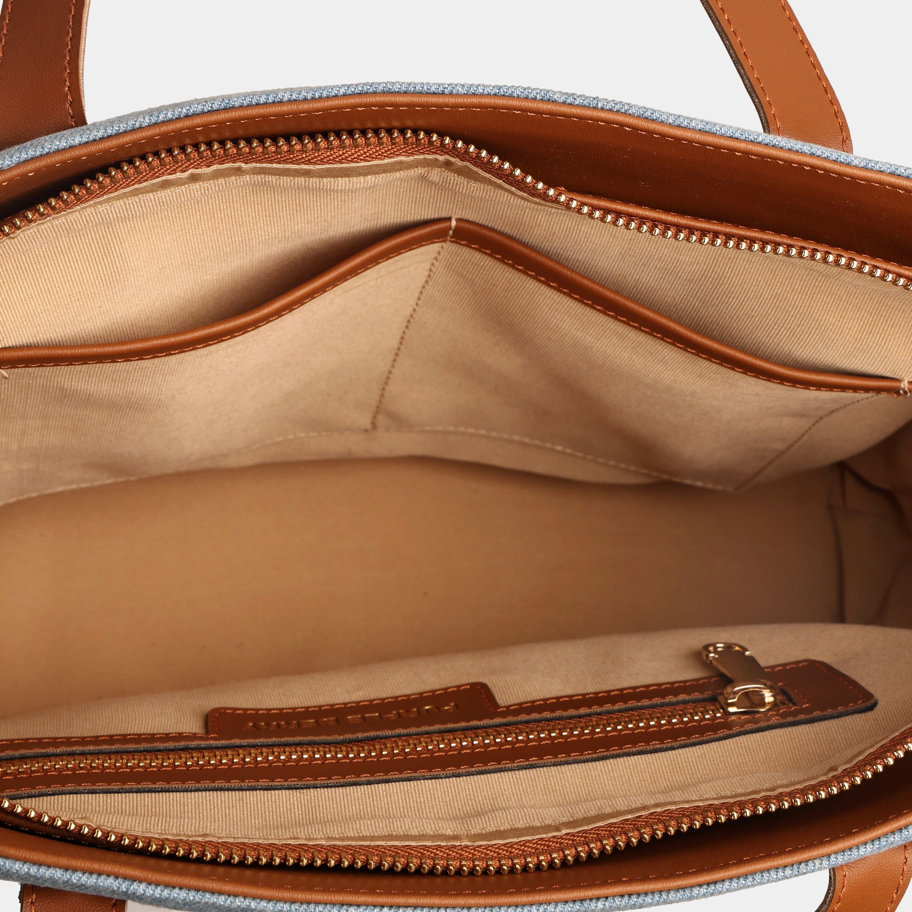 Interior compartment of light blue Harper denim handbag with two slip pockets and secure zipper pocket