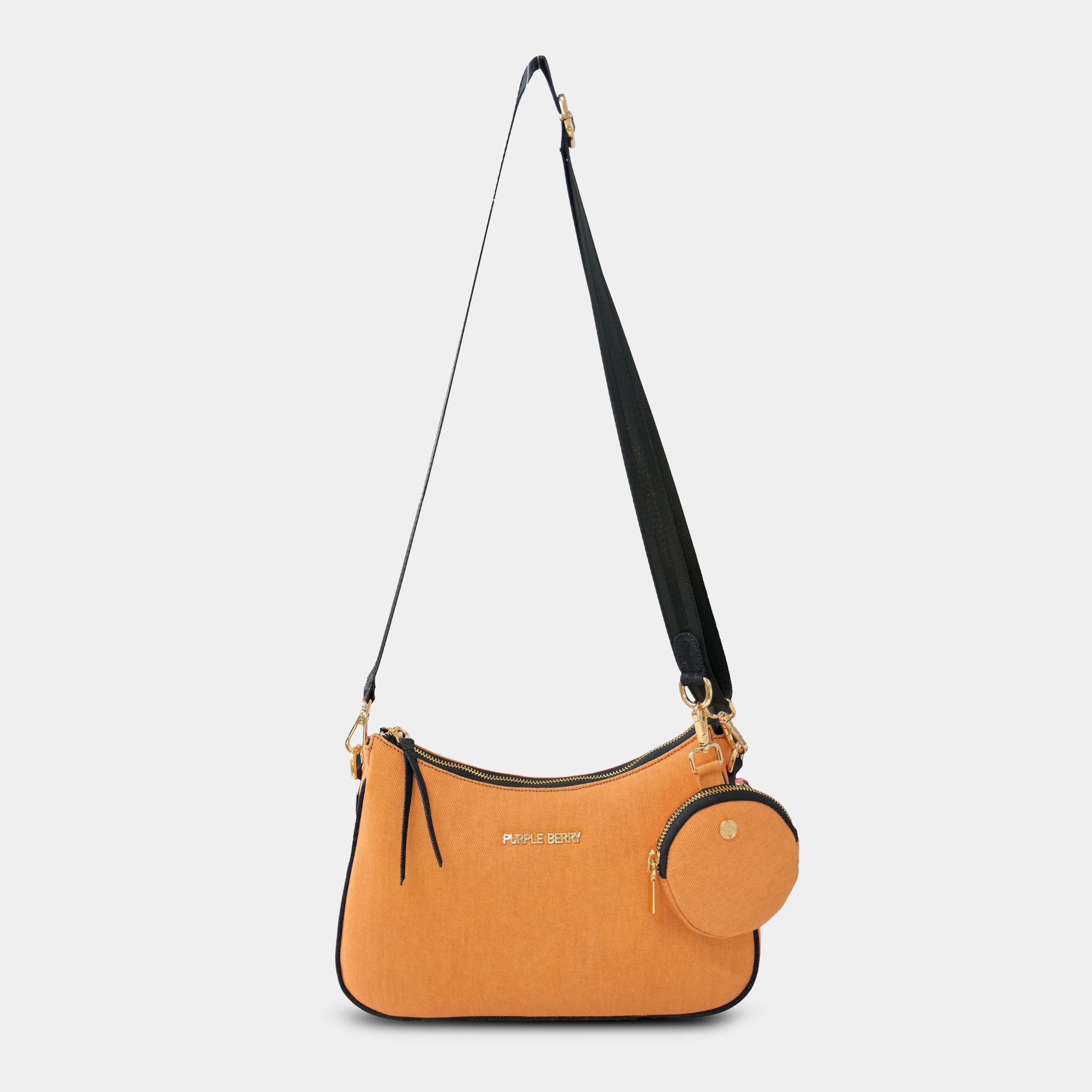 Front hanging view of orange Bili denim sling bag with curved body and gold hardware