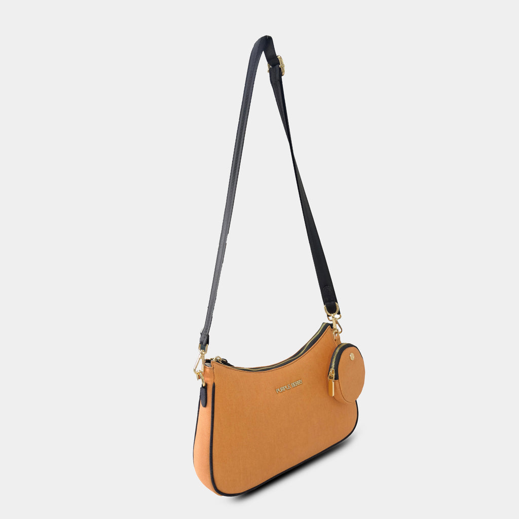 Side angle of orange Bili denim crossbody bag highlighting curved design and strap