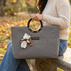Woman holding grey denim tote by circular handles