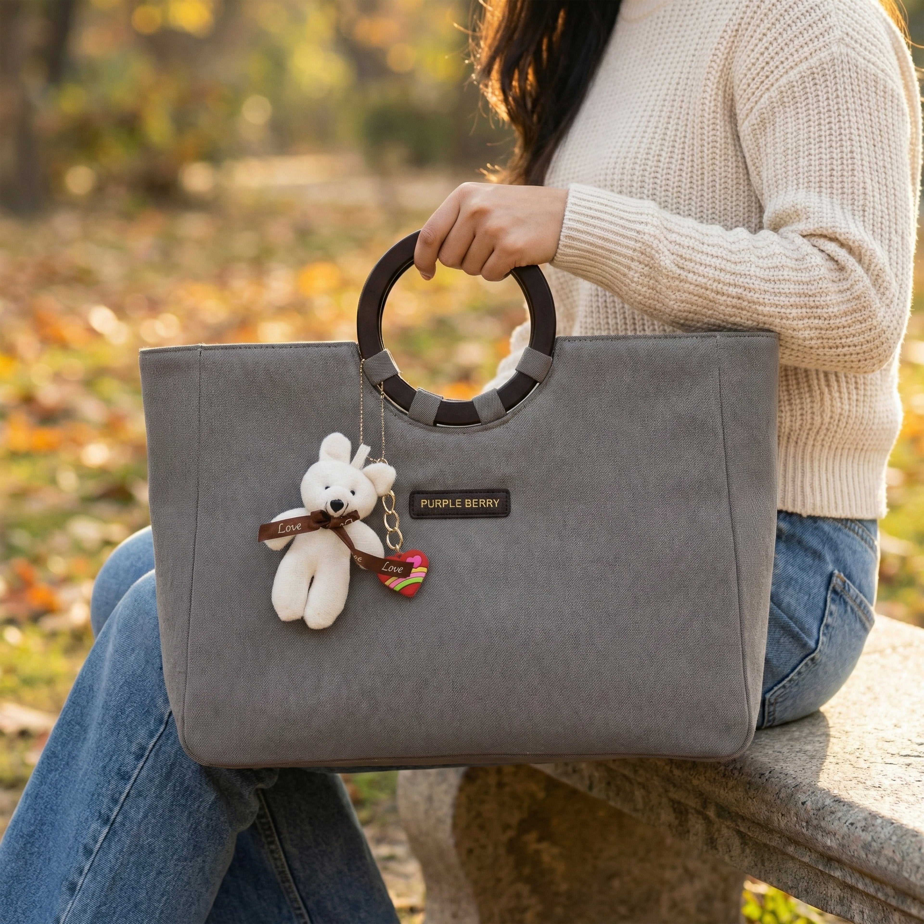 Woman holding grey denim tote by circular handles