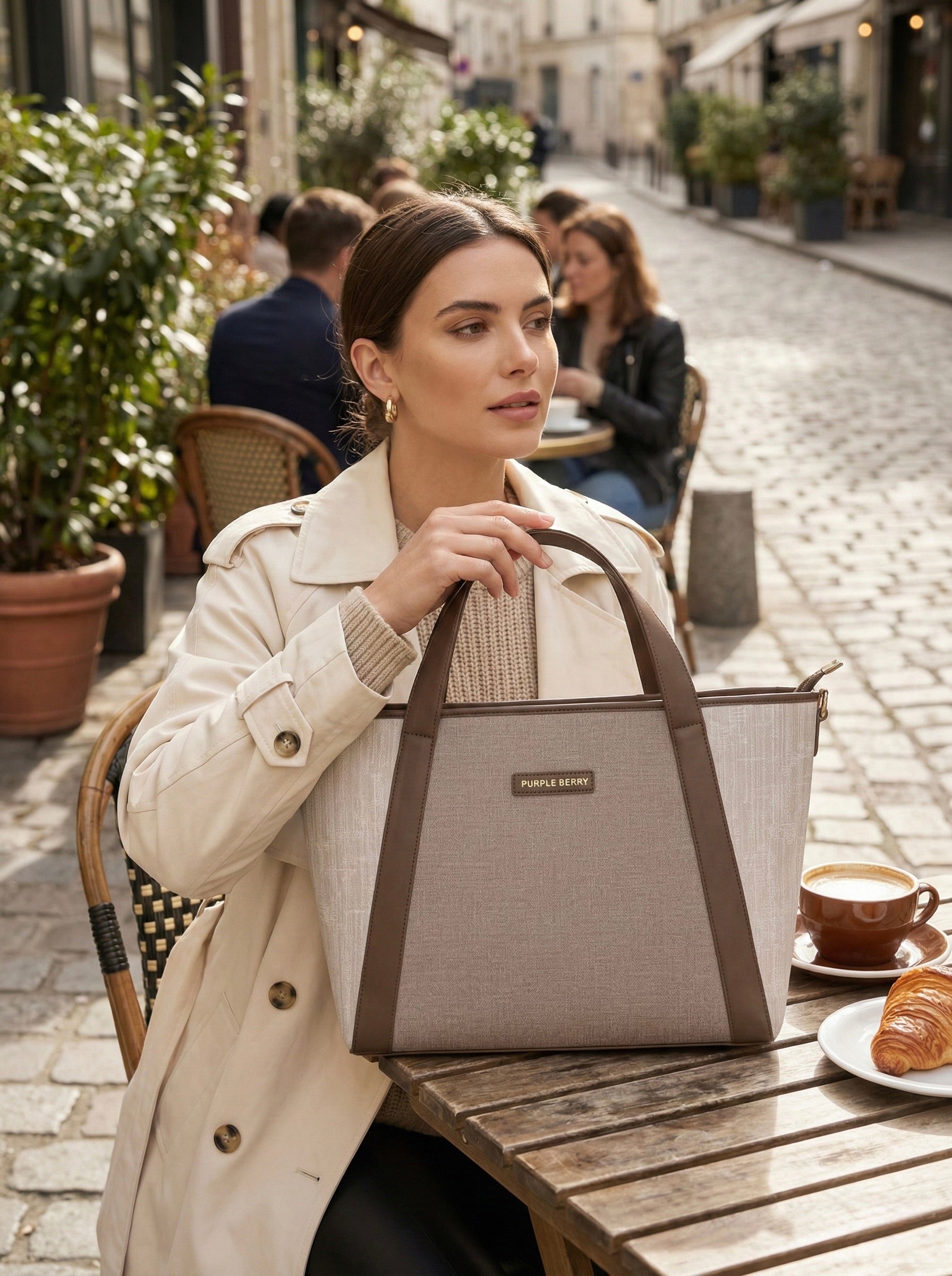 Woman sitting at café holding beige Lexie Office Tote bag