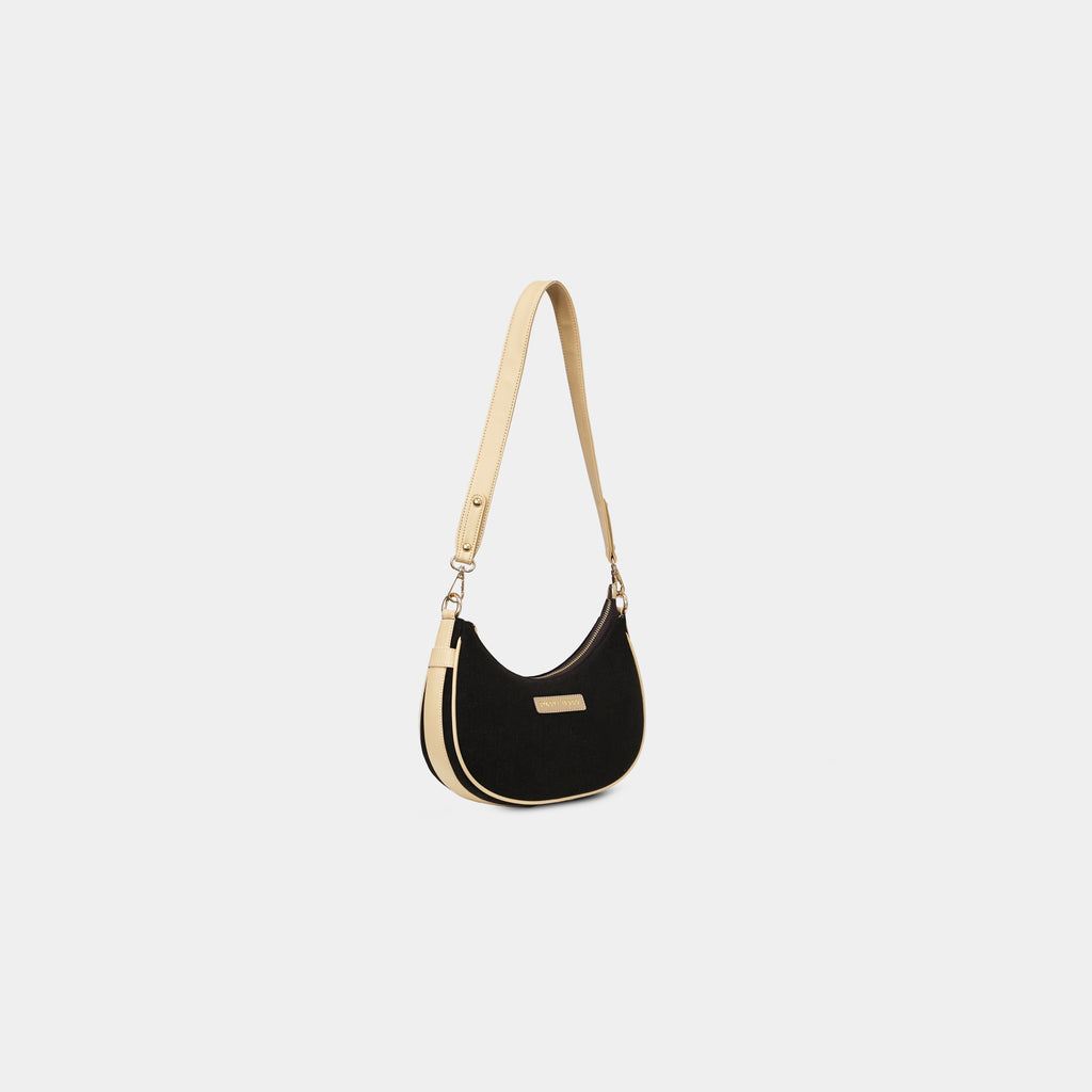 Angled view of Purpleberry Moda black crescent denim sling bag