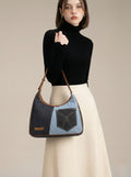 Woman holding a denim Shoulder bag against a neutral background

