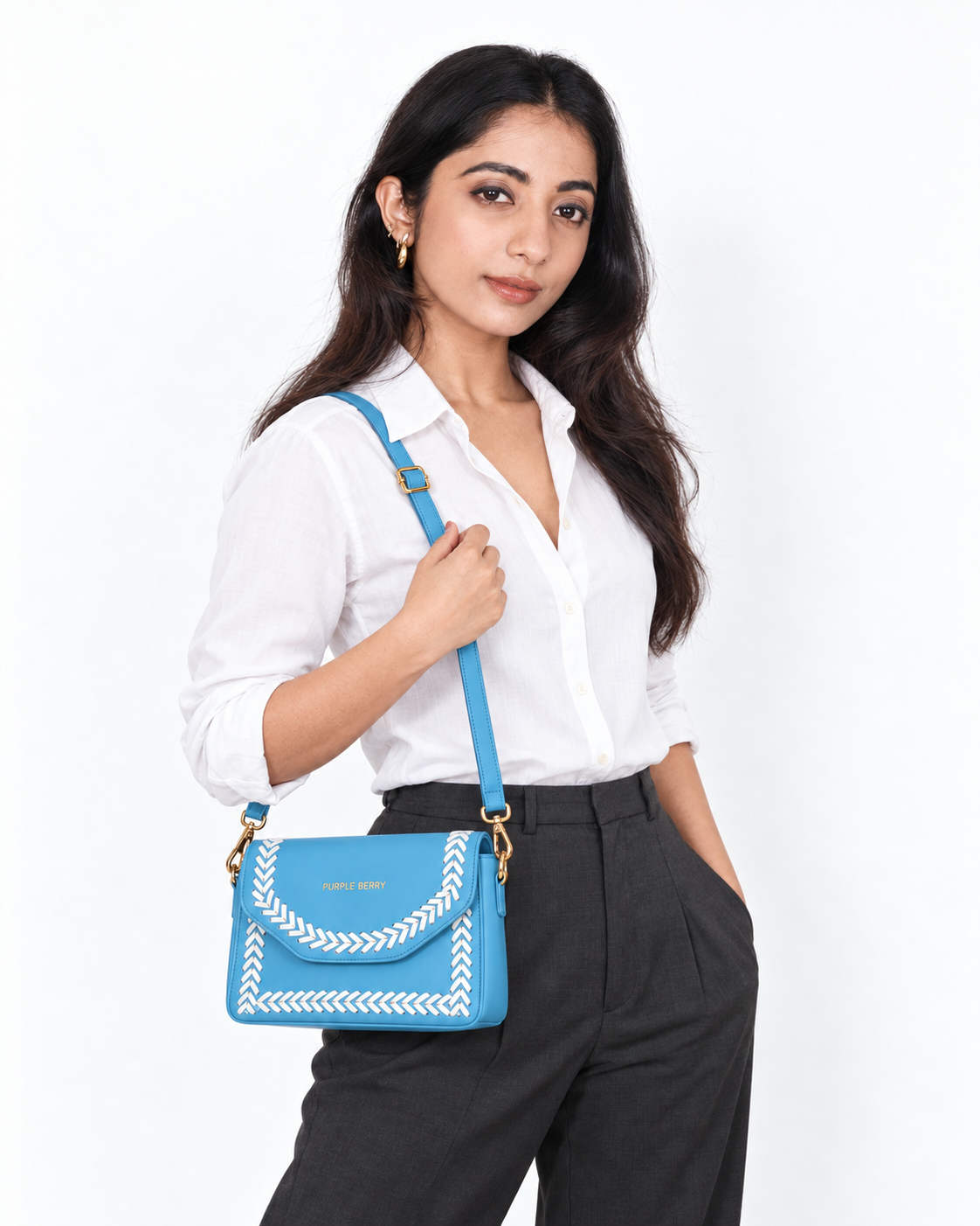 Model in a white shirt carrying the Purpleberry Riva sky blue sling bag with white cross-stitch detailing.