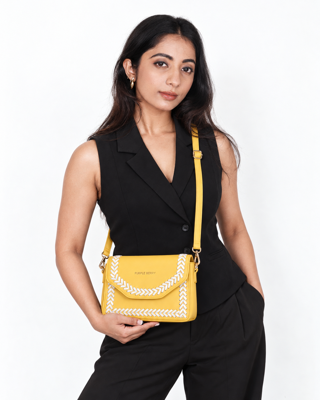 Model in a black waistcoat holding the Purpleberry Riva yellow sling bag with white cross-stitch detailing.
