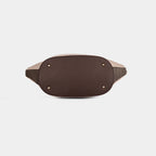 Bottom view of beige Siena handbag featuring four protective metal base studs and structured base