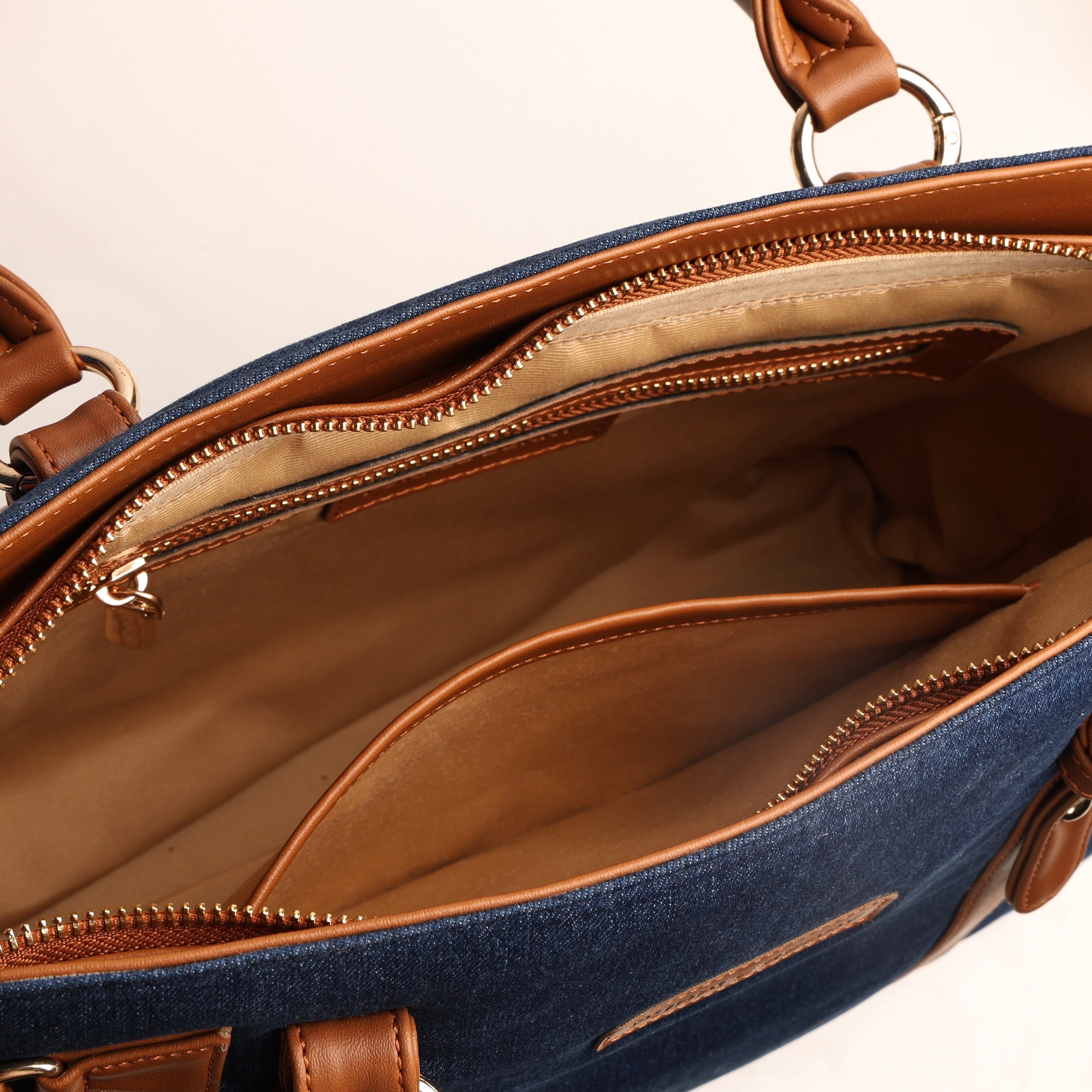 Spacious interior of deep navy denim handbag with zipper pocket and slip pocket compartments
